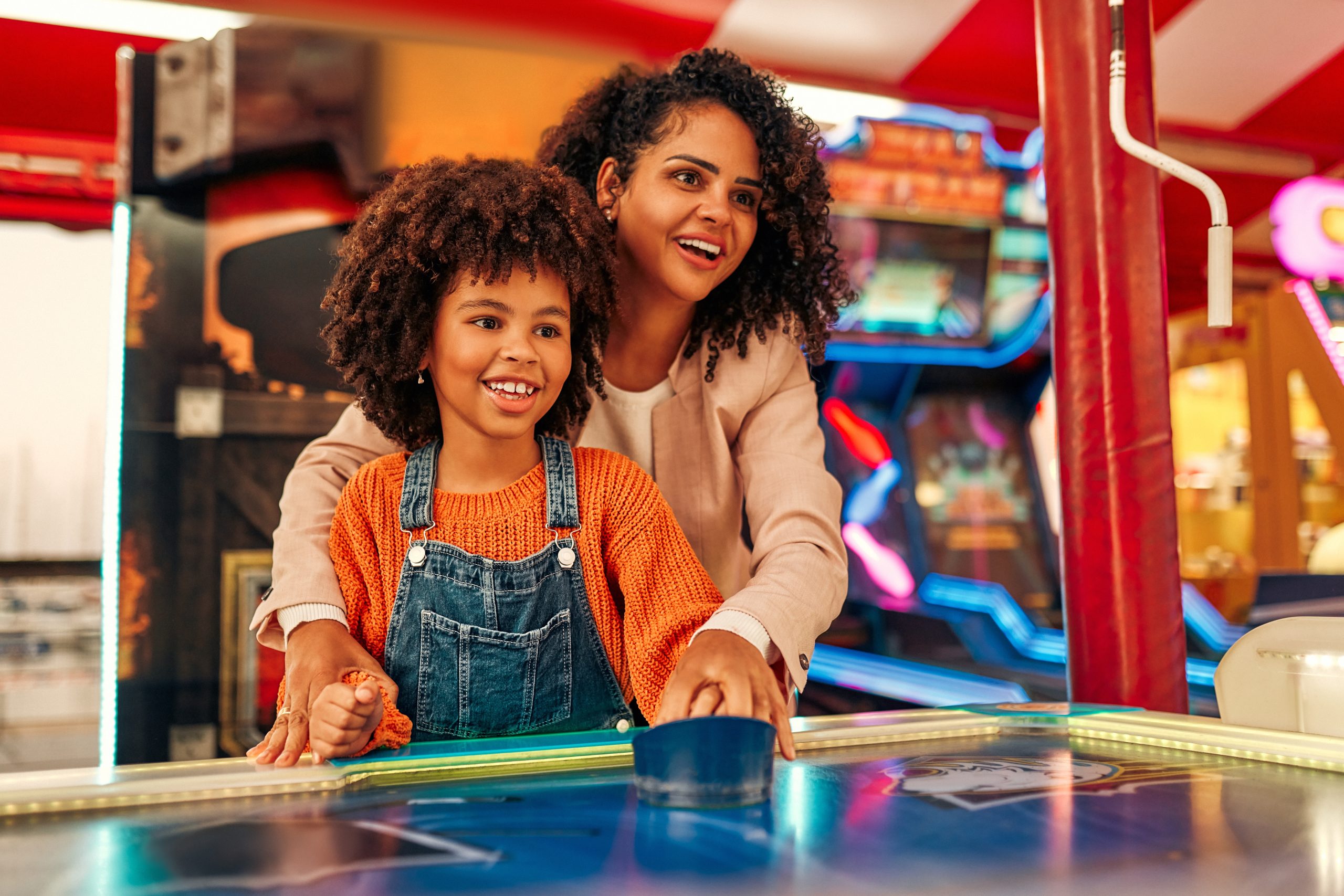 A cute child with with her mother playing air hockey